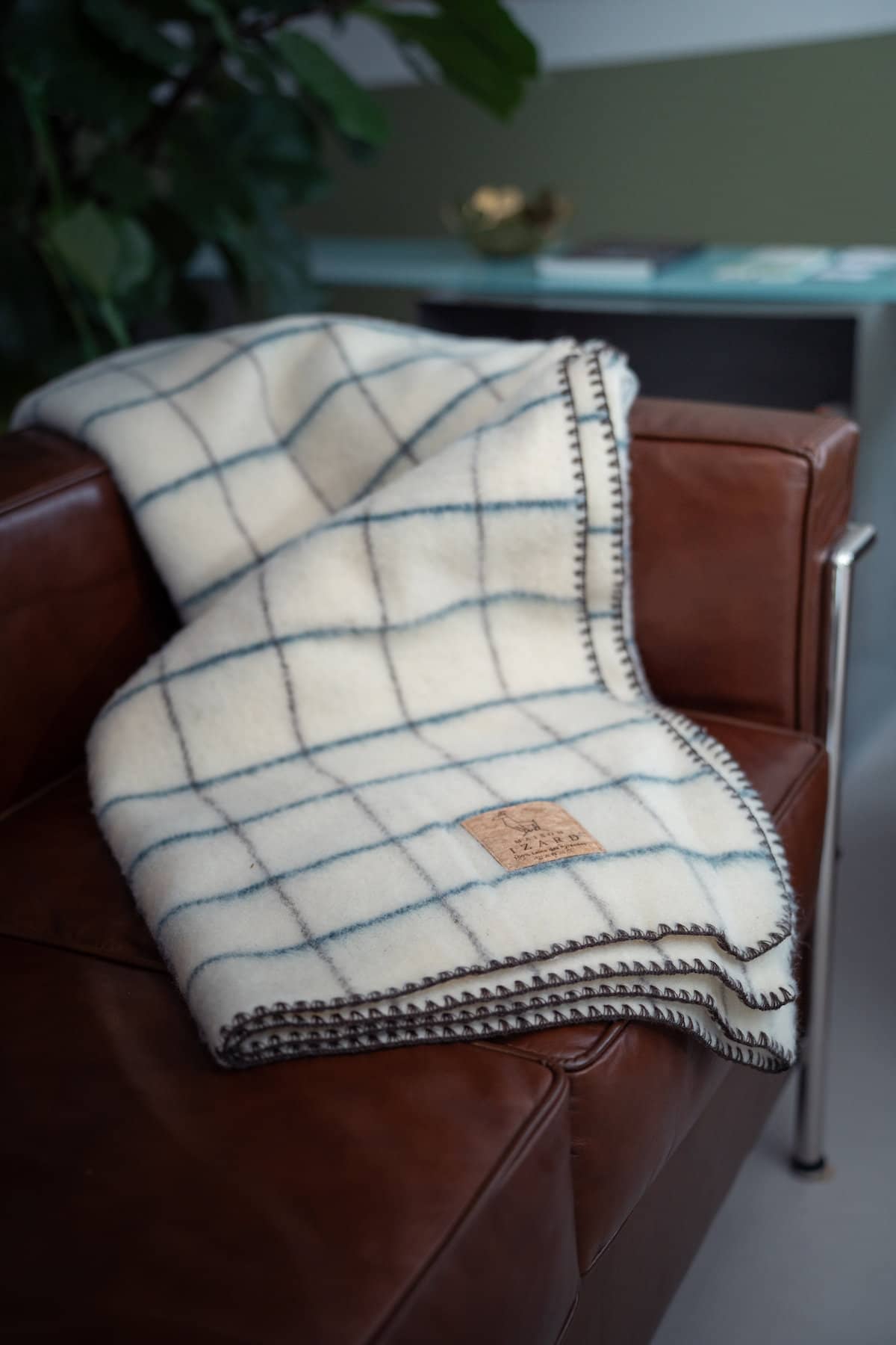 Plaid Calou écru à carreaux bleu paon et marron posé sur un canapé