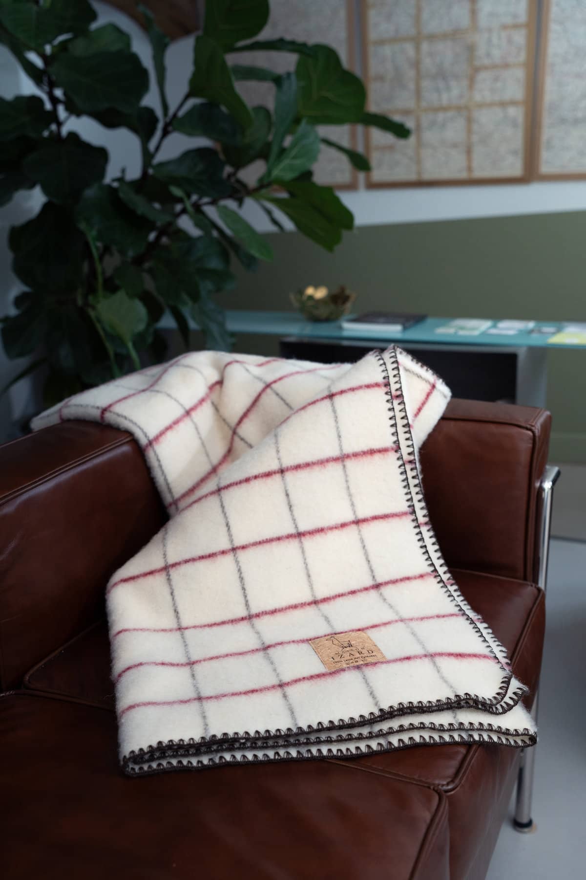 Plaid Calou laine française écru à carreaux bordeaux et marron posé sur un fauteuil
