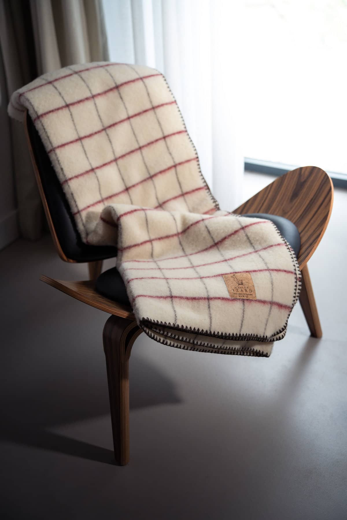 Plaid Calou écru à carreaux bordeaux et marron posé sur un canapé made in france