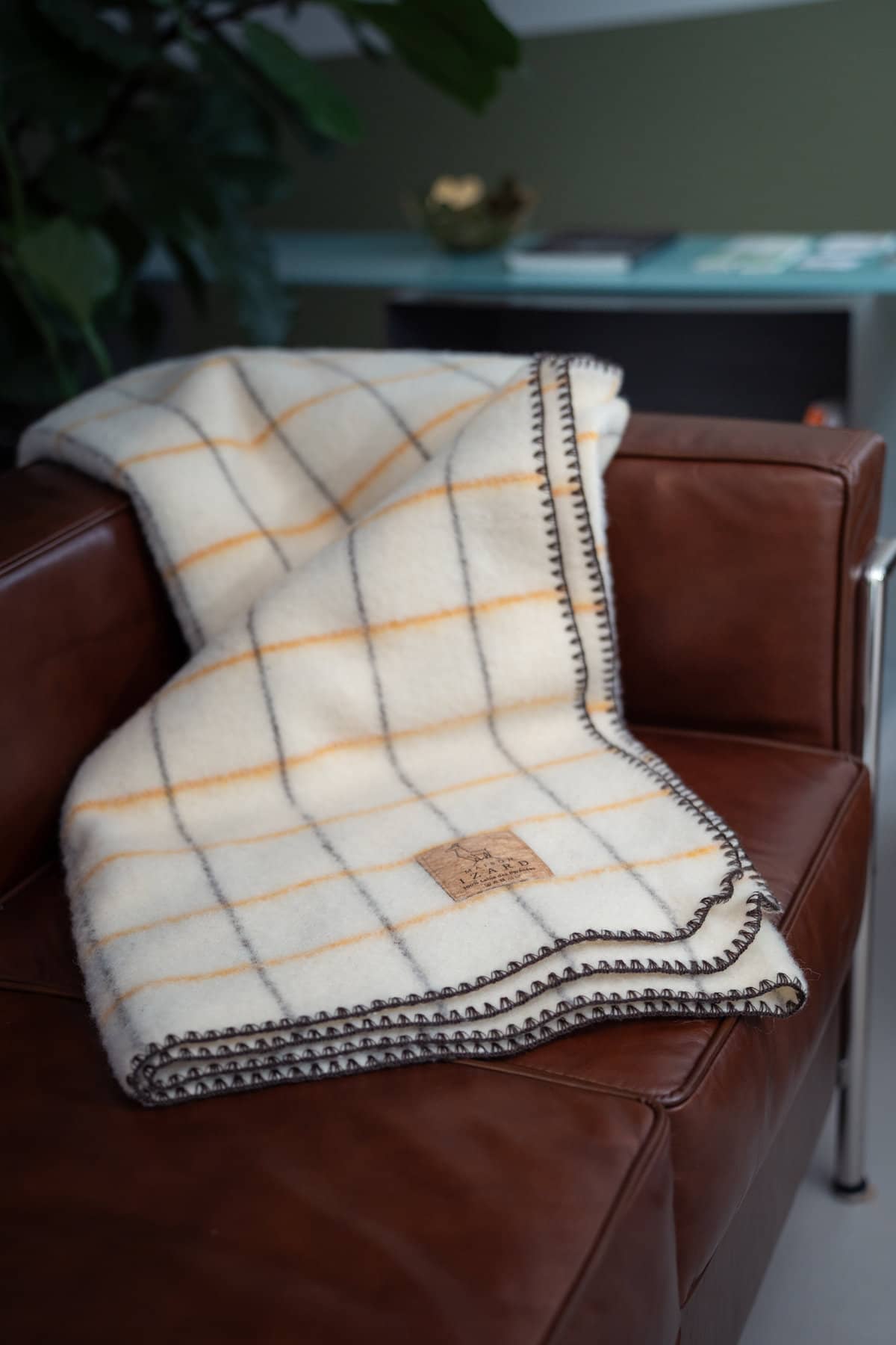 Plaid Calou écru à carreaux jaune et marron posé sur un fauteuil made in france