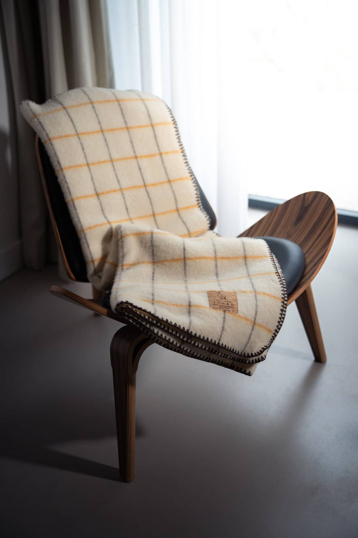 Plaid Calou laine française écru à carreaux jaune et marron posé sur un canapé