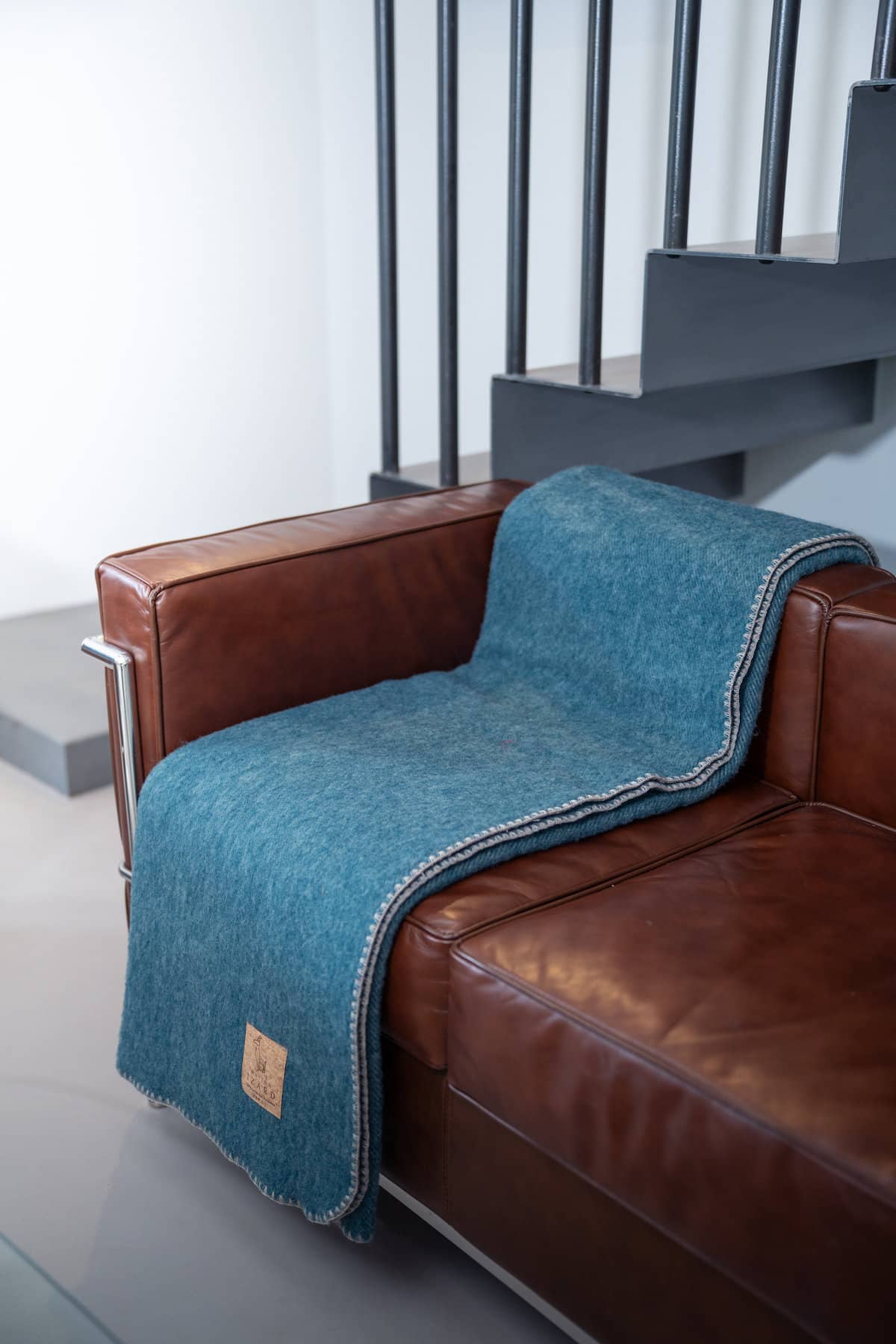 Plaid Calou bleu paon en laine française posé sur un canapé