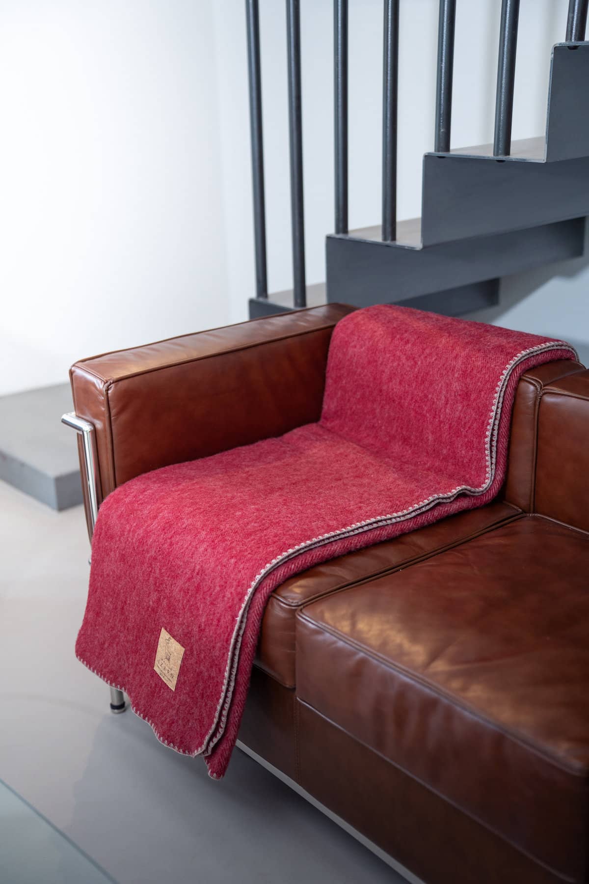 Plaid Calou bordeaux en laine française posé sur un canapé