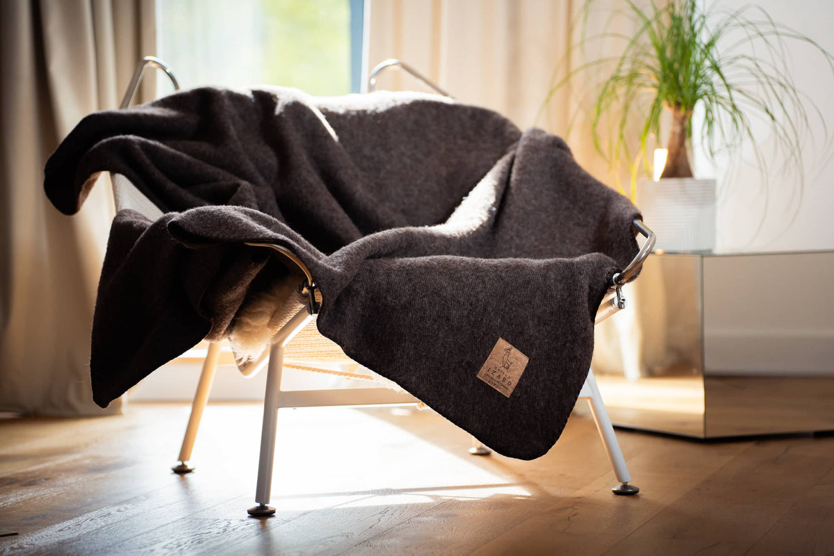 Plaid marron en laine française Calou posé sur un fauteuil.