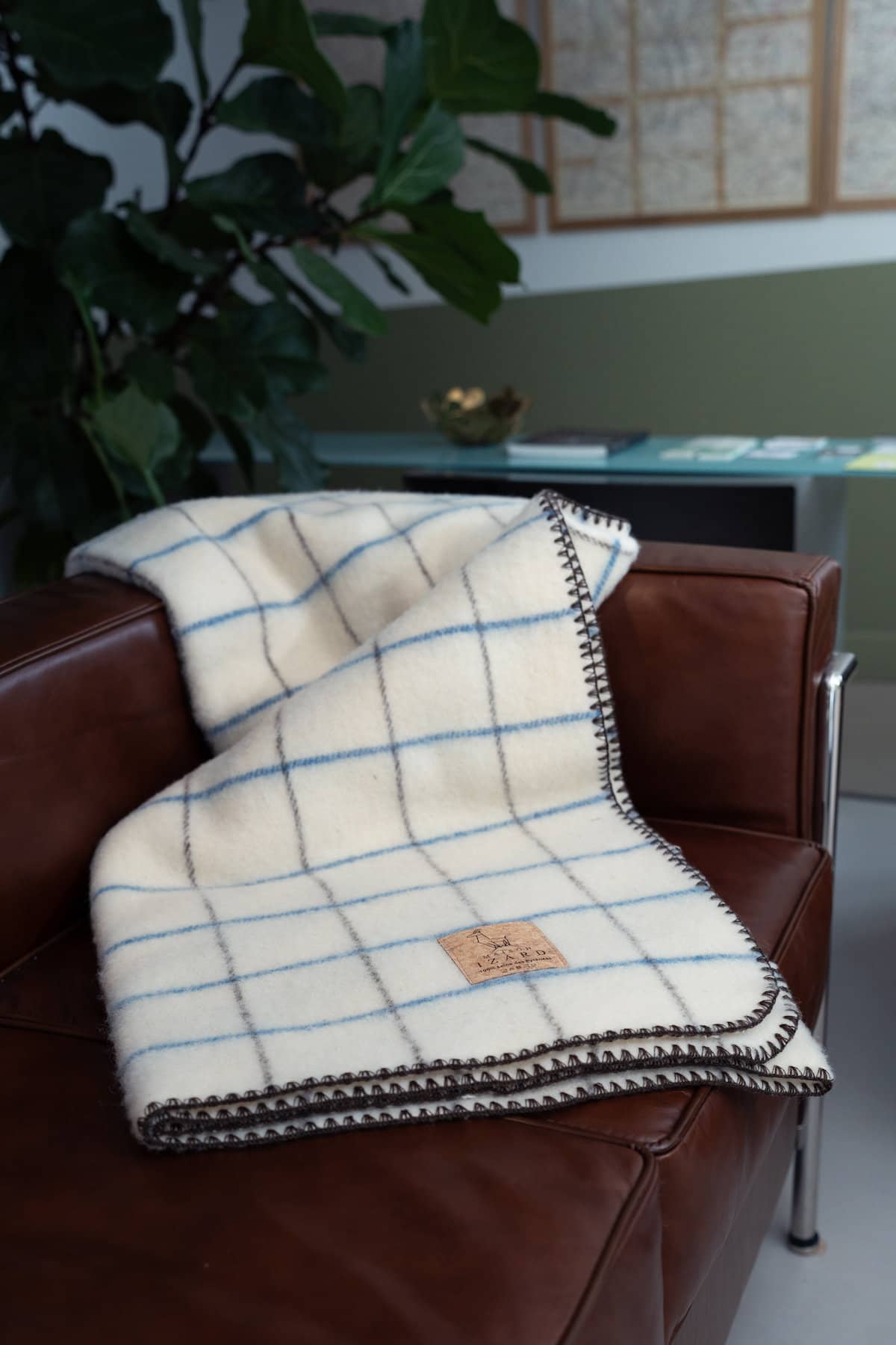 Plaid Calou laine française écru à carreaux bleu et marron posé sur un fauteuil