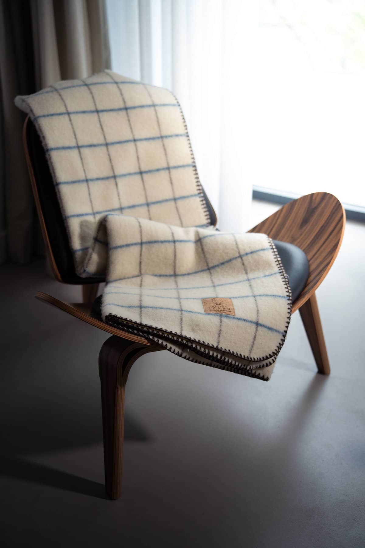 Plaid Calou laine française écru à carreaux bleu et marron posé sur un canapé