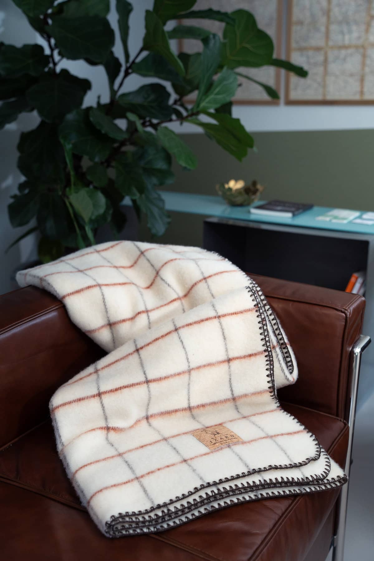 Plaid Calou écru à carreaux terracotta et marron posé sur un fauteuil made in france