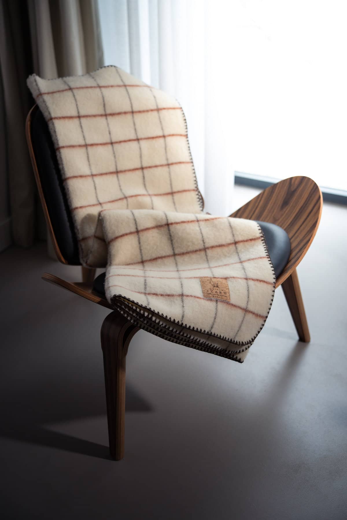 Plaid Calou laine française écru à carreaux terracotta et marron posé sur un canapé